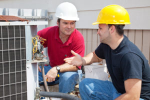 Air conditioning repairmen discussing the problem with a compressor unit of commercial air conditioning systems