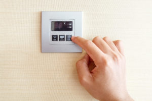 Hand with finger on a thermostat to control refrigerated air