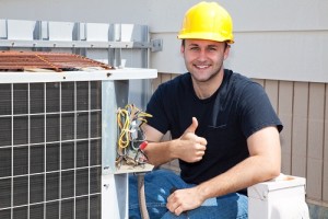 smiling technician kneeling next to an hvac system