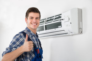 Technician standing next to a fixed AC unit with a thumbs up sign
