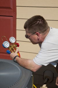 air conditioner repair being done by a technician, as he checks freon levels of an outdoor unit