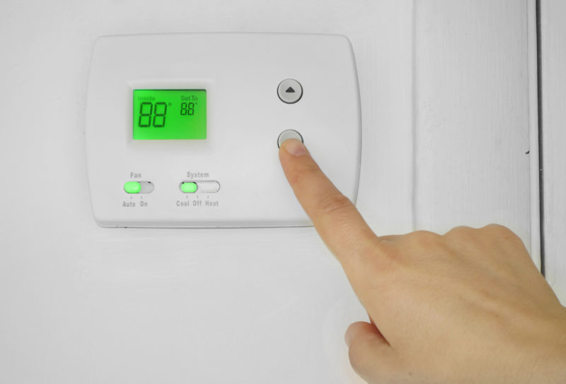 Person adjusting the AC thermostat temperature