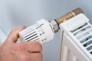 close-up of a hand setting the temperature on a heater thermostat